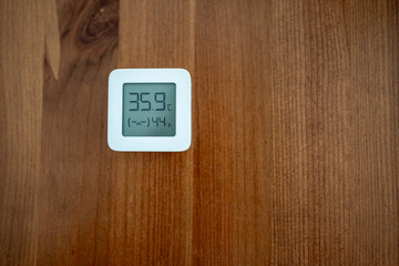 Thermometer showing very high temperatures indoors on wooden table.