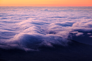 Colorful sunrise sky with dramatic waves of clouds over coastline