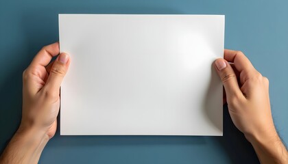 Hands holding a blank white card on a pastel blue background.