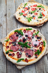 2 pizza with mozzarella cheese , salami sausages , olives , chicken , pineapple and tomatoes