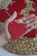 Hand holding red paper heart garland.