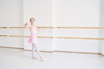 Naklejka premium Young ballet girl at studio lesson. Training performance. Stretching exercise pose. Ballerina practice balance technique. Classical elegance fitness. Dancing costume. Pink dress, skirt