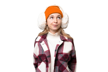 Young  English woman wearing winter muffs over isolated background and looking up