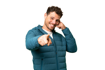 Brazilian man over isolated chroma key background making phone gesture and pointing front