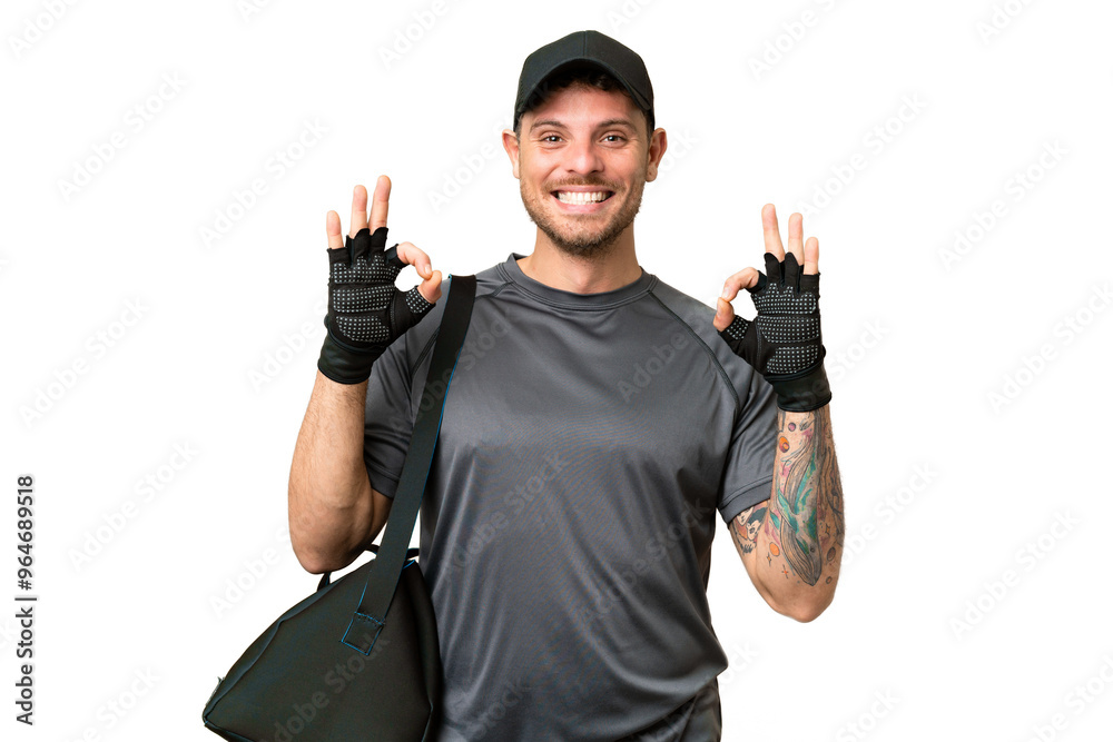 Wall mural young sport man with sport bag over isolated chroma key background showing an ok sign with fingers