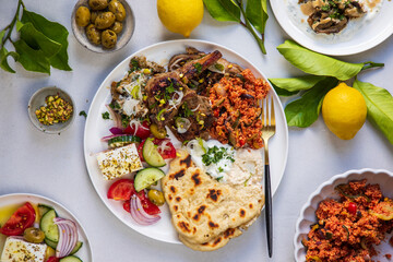 Greek food, lamb chops with couscous, feta salad, hummus and flat breads