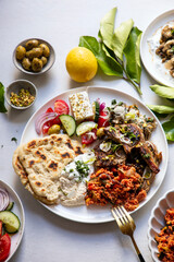 Greek food, lamb chops with couscous, feta salad, hummus and flat breads