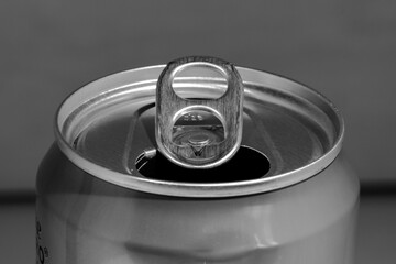 Horizontal black and white photograph of the top of an opened metal can of drink.