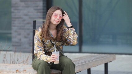 Pensive happy woman sipping a milkshake in the street