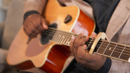 Guitar playing. Song performance. Blues music. Talented man artist hands practicing jazz chords on acoustic string instrument with capo indoors.