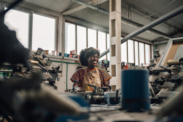 Diverse graphic worker is silkscreen printing on machine at workshop.