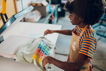 Smiling diverse graphic worker working on heating press at factory.