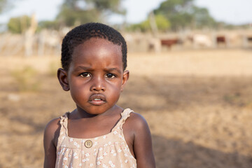 village african herder cattle, african child girl standing in front of the cows pen