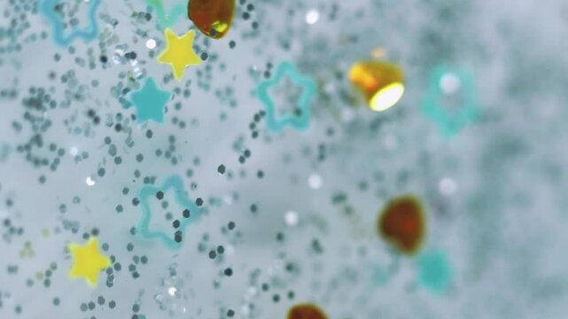 Shimmer fluid. Glitter shapes. Defocused gray yellow golden blue silver color stars figures sparkling crystal jeweled heart float spangles bokeh abstract art background.