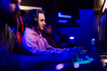 Side view of gamer with headset playing fps pvp online arena at cybercafe