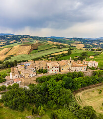 Fototapeta premium An aerial view westward toward the hilltop fortress village of Sant Andrea di Suasa, Italy in summertime