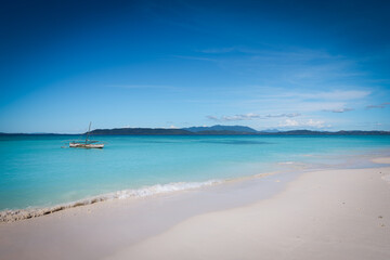 Experience the serene beauty of Paradise Beach on Nosy Be with crystal-clear waters and gentle waves under a clear sky