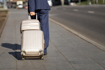 confident businesswoman in a blue suit gracefully maneuvers two wheeled suitcases, embodying determination and style. Ready for her next adventure, she blends professionalism with sophistication