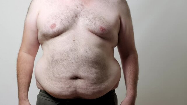 A close-up video of an overweight man rubbing his belly and shaking his body fat, showing the movement and texture of his skin