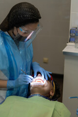 Close-up view of dentist in blue gloves doing teeth exam in open with cheek retractor mouth of...