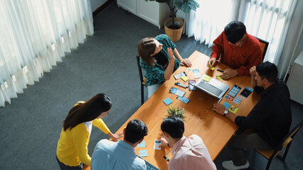 Top view of business team writing sticky notes while manager working on tablet and looking at analysis data. Group of diverse people sharing or exchanging marketing plan. Creative work. Convocation.