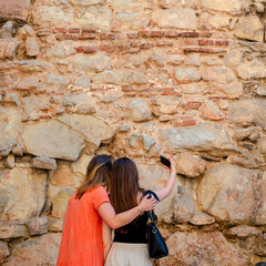 Two young ladies take selfies on their mobile