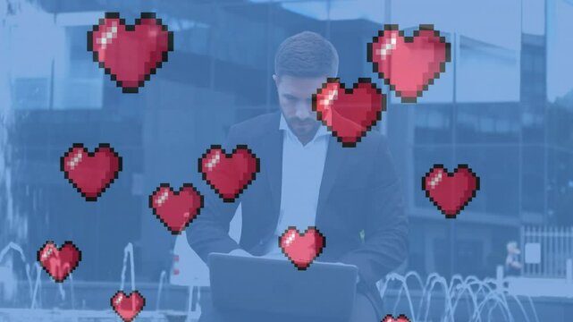 Animation of heart icone over caucasian businessman using laptop