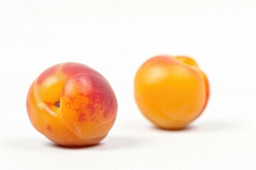Fresh peaches sit adjacent on a clean white surface, perfect for still life photography or fruit display