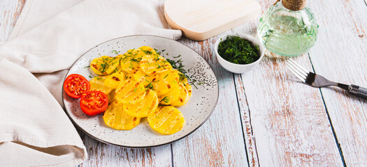 Appetizing grilled potatoes with tomatoes and dill on a plate on the table web banner