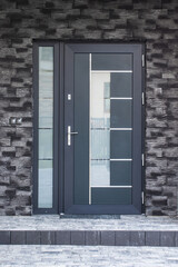 Fototapeta premium Facade of a modern building with modern doors. Designer entrance door to a country house. Modern design. Luxurious exterior.