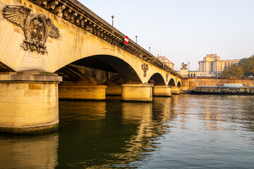 Obraz premium The view captures the Jena Bridge arching over the Seine River, reflecting the soft light of early evening. The detailed stone carvings add historical charm to this iconic Parisian location.