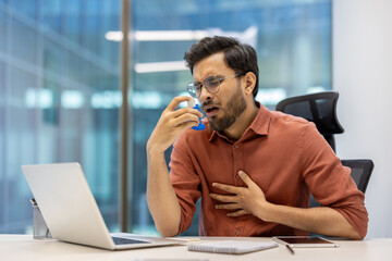Man in office experiencing asthma symptoms using inhaler for relief. feeling discomfort. Scene...