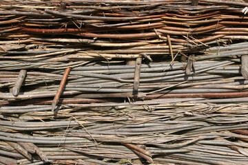 Wicker fence with tree branches texture close up. Sturdy wattle fence, continuously woven willow fence. Organic material, brushwood weaving barrier crafting