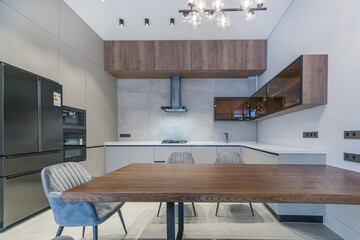 The interior of the kitchen with an exquisite design. The cabinets and countertop of the .kitchen set are decorated in white, hanging cabinets and a table made of dark wood. Modern household appliance