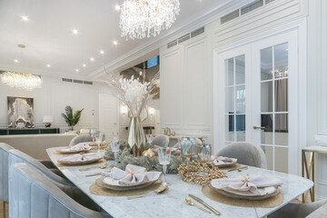A table with an elegant setting in the interior of a luxurious living room in a neoclassical .style. White room decor.