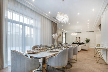 Magnificent interior design of the living room of a luxurious mansion. Elegant table .setting. Panoramic windows with beautiful curtains.