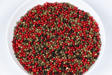 A mixture of different peppercorns on a white background