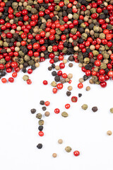 Red, green, white and black peppercorns on a white background top view.