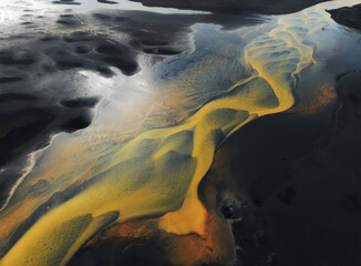 Beautiful Icelandic yellow river flowing into black sand beach