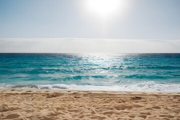 Fototapeta premium Golden sand meets azure waters, pristine beach under clear, sunny sky, serene scene