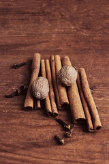 fragrant cinnamon sticks, nutmeg and clove buds on a wooden background close-up, top view