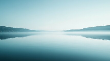 Fototapeta premium Misty Morning Landscape with Calm Water and Distant Forested Hills
