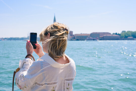 Girl taking a photo on sunny day in Venice, italy