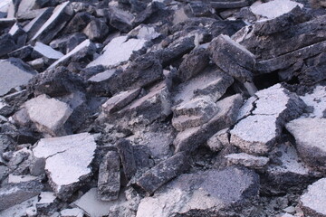Close-up chunks of asphalt lie in a heap view from above. Road repair works