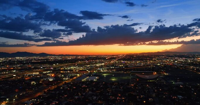 Luminous panorama of Phoenix, Arizona, the USA at twilight. Flying above the vast cityscape under the orange skies.