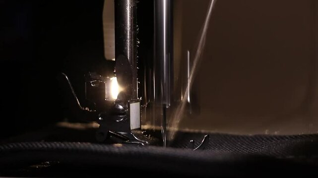 A girl sews on a sewing machine at night in the dark by the light of a lamp, sewing on a sewing machine