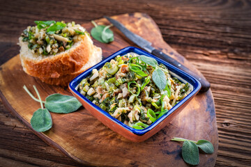 Traditioneller italienischer Toskana Aufstrich mit Steinpilzen und Frühlingszwiebel fein gehackt auf frischen knusprigen Baguette Scheiben und in einer Schale serviert als Nahaufnahme