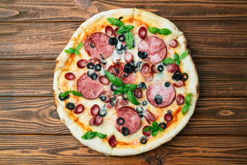 Pizza with mozzarella cheese , salami sausages , olives , and basil