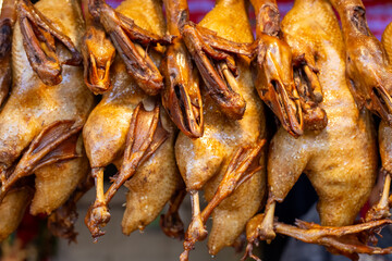 Thai cuisine. Grilled ducks hang at the market. Street food.