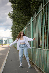 Beautiful girl with long hair rollerblading in park. Roller skating quads - popular and safe type...
